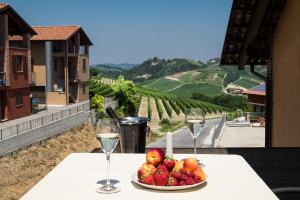 a table with a bowl of fruit and two glasses of wine at Costa Catterina B&B in Castagnito