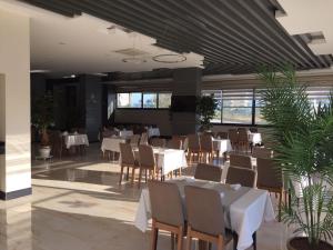 un restaurante con mesas blancas, sillas y plantas en Siberland Olive Garden Orion City 7 en Avsallar