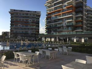 a patio with tables and chairs and two tall buildings at Siberland Olive Garden Orion City 7 in Avsallar