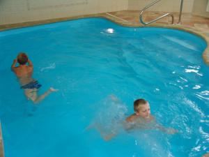 twee jonge jongens zwemmen in een zwembad bij Penzion Martin in Janske Lazne