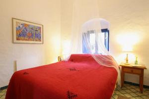 1 dormitorio con cama roja y ventana en Casas Karen, en Los Caños de Meca