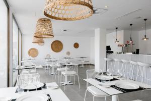 a restaurant with white chairs and tables and a chandelier at AluaSoul Ibiza - Adults only in Es Cana