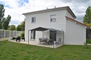 Cette maison blanche dispose d'une terrasse avec des tables et des chaises. dans l'établissement La Marina, à Chassieu