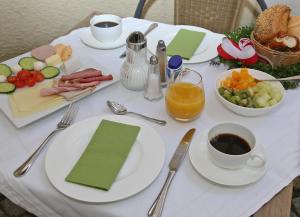 a white table with plates of food and a bowl of fruit at Stadthotel Herzog Ludwig in Landshut