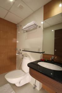 a bathroom with a toilet and a sink and a mirror at Hotel Aquarius in Vaikom