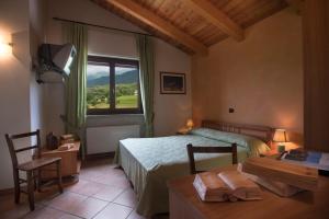 a bedroom with a bed and a table and a window at Hotel la Colletta in Paesana
