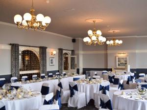 a room with white tables and chairs and chandeliers at The North Euston Hotel in Fleetwood