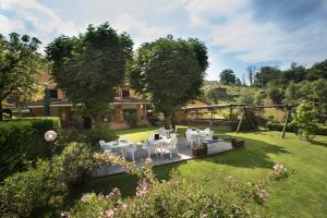 Hotel la Colletta في Paesana: صورة حديقة فيها طاولات وكراسي بيضاء