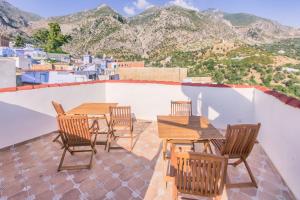 a patio with wooden tables and chairs and mountains at Dar Swiar in Chefchaouen