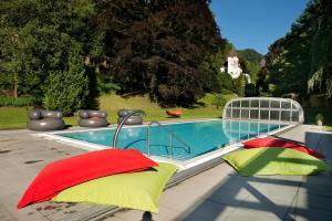 una piscina con almohadas rojas y verdes junto a ella en Hotel Schloss Ragaz en Bad Ragaz