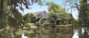 una casa con un lago delante de ella en Hotel Restaurant Huxmühle, en Osnabrück