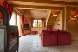 ein Wohnzimmer mit einer roten Couch in einer Hütte in der Unterkunft Les Chalets du Danay in Saint-Jean-de-Sixt