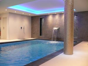 a swimming pool with a waterfall in a hotel room at Les Criquets Hôtel & Spa in Blanquefort +79 photos
