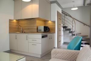 a kitchen with white cabinets and a stair case at Preilos Vėtra 1 in Preila