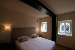 una camera da letto con un grande letto bianco con due finestre di Cortile nel borgo a Marina Palmense