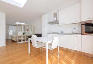 una cucina e una sala da pranzo con tavolo e sedie bianchi di La Maison del Capestrano a Milano