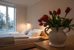 a vase with red flowers on a table next to a bed at Baltica Residence in Sopot +29 photos