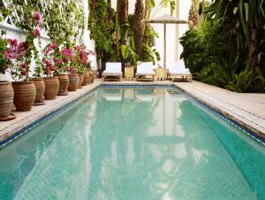 una piscina con sedie, fiori e piante di Riad L'Hôtel Marrakech a Marrakech