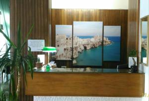 a store counter with four paintings of a city at Hotel 2 Mari - Vieste in Vieste