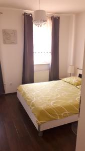 um quarto com uma cama com um edredão amarelo e uma janela em Apartment Meli em Sesvete