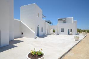 a white house with a courtyard with potted plants at Apartments Naxos Camping in Naxos Chora