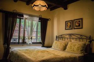 a bedroom with a bed with a window and a chandelier at Guest House Verbena in Apriltsi