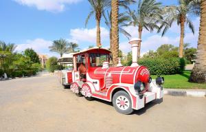 un moteur de train rouge garé dans un parc planté de palmiers dans l'établissement Stella Di Mare Sea Club Hotel, à Ain Sokhna