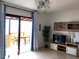a living room with a tv and a sliding glass door at El Granillo G-96 in Costa Calma