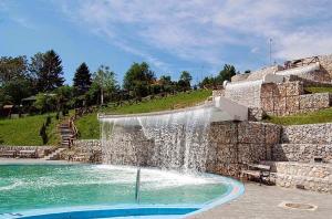a waterfall in a swimming pool next to a stone wall at AMAI Exclusive in Tuzla