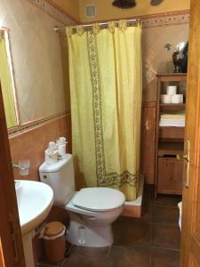 a bathroom with a toilet and a yellow shower curtain at Casa Rural El Rincón de Antonia in Agulo
