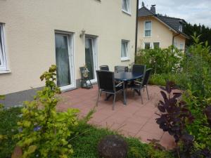 eine Terrasse mit einem Tisch und Stühlen vor einem Haus in der Unterkunft Ferienwohnung Mai in Plettenberg