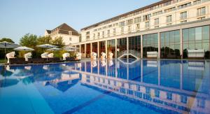ein Hotel mit einem großen Pool vor einem Gebäude in der Unterkunft A-ROSA Travemünde in Travemünde