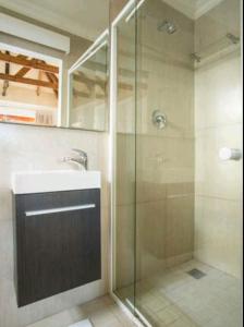 y baño con ducha acristalada y lavamanos. en Milnerton Guesthouse en Ciudad del Cabo