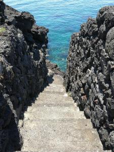 una escalera que conduce al océano en un acantilado rocoso en Il Giardino Dei Limoni, en Aci Castello