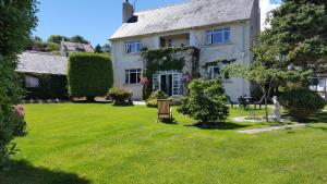 a white house with a lawn in front of it at Wychwood House in Tenby