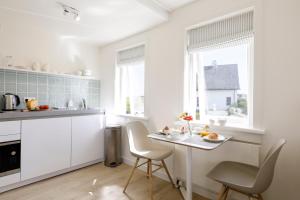 a kitchen with white cabinets and a table and chairs at Villa Parnassia in Bergen aan Zee