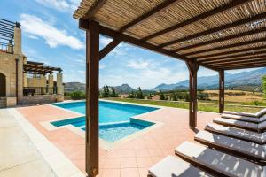 una piscina all'aperto con pergolato in legno di Thalia Villa, majestic landscape of South Crete, By ThinkVilla a Lefkogeia