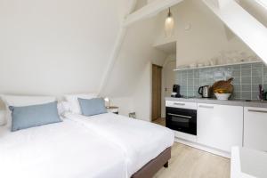 a bedroom with a white bed and a kitchen at Villa Parnassia in Bergen aan Zee