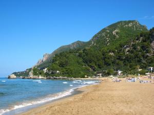 a beach with people and the ocean and a mountain at Malibu in Glyfada
