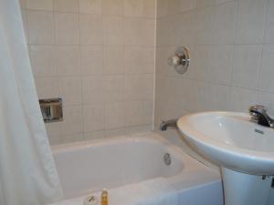 y baño con bañera blanca y lavamanos. en St. Norbert Hotel, en Winnipeg