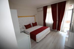 アーブシャ島にあるYürekli Apart Hotelの小さなベッドルーム(ベッド1台、赤いカーテン付)