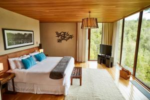 um quarto com uma cama grande e uma televisão em Uman Lodge Patagonia Chile em Futaleufú
