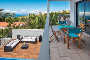 ein Balkon mit einem blauen Tisch und Stühlen und einer Couch in der Unterkunft Villa Enjoy - by LovelyStay in Lombo da Velha