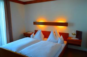 a bedroom with a bed with white sheets and pillows at Hotel Kristall in Kleinarl