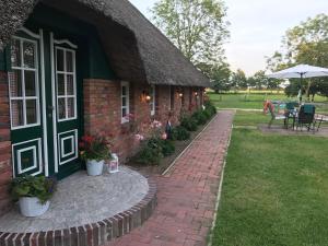 ein Backsteinhaus mit einem Strohdach und einer Terrasse in der Unterkunft Ferienwohnung Süderfeld in Brake