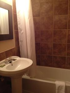 a bathroom with a sink and a toilet and a tub at Chomedey Inn in Laval