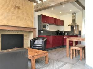 a kitchen with red cabinets and a table and a couch at Hameau de la Fausse Sauge in Mézilles