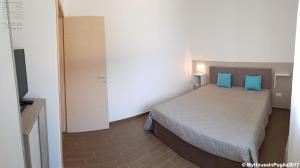a bedroom with a bed with blue pillows and a television at Case Vacanza Marzano in Monopoli