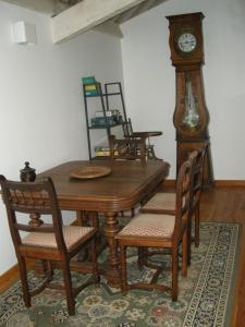 ein Esszimmer mit einem Holztisch und einer Großvater-Uhr in der Unterkunft Auberge BRIASSOU in Grazac