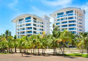 two tall buildings on the beach with palm trees at Diamante del Sol 203S in Jacó